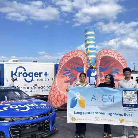 A blue race car, a sculpture of a lung, and students holding a sign