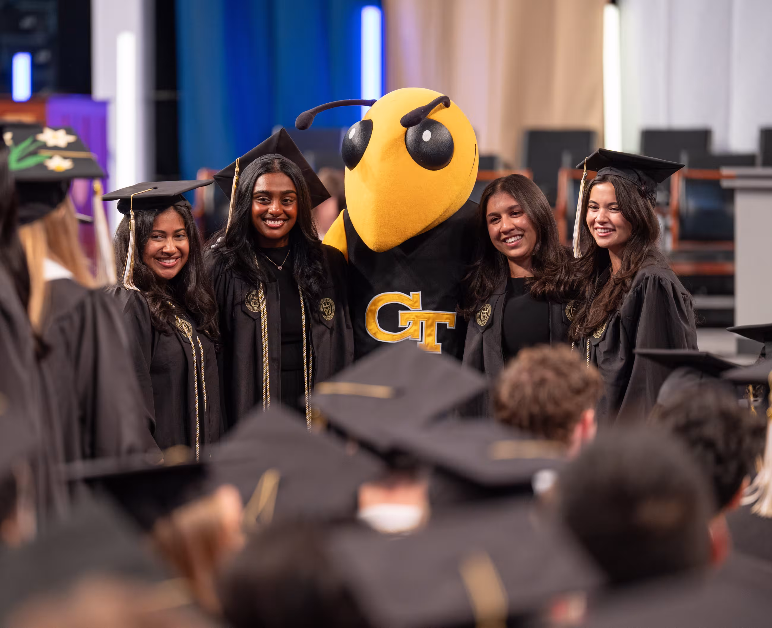 Four graduates take a photo with Buzz before the Georgia Tech Commencement ceremony
